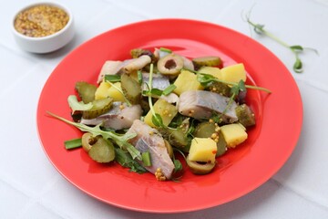 Delicious salad with herring on white tiled table, closeup