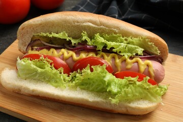 Tasty hot dog with vegetables on black table, closeup