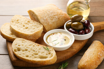 Sliced bread with oil, olives and spices on wooden table, closeup