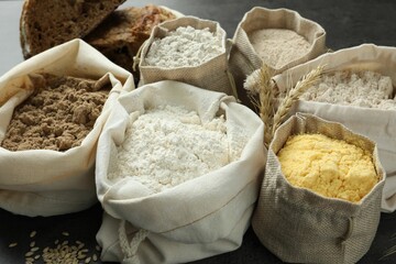 Different types of flour in bags on grey table, closeup