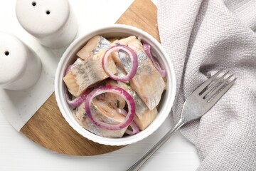 Pieces of delicious herring with onions on white table, top view