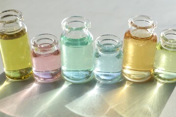 Perfume bottles with aromatic oils on light background, closeup