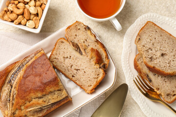 Cut banana bread with nuts and tea on light grey table, flat lay