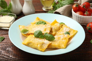 Delicious ravioli with cheese and basil served on wooden table, closeup