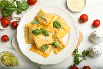 Delicious ravioli with cheese and basil served on white marble table, flat lay