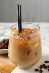 Tasty iced coffee and beans on white marble table, closeup