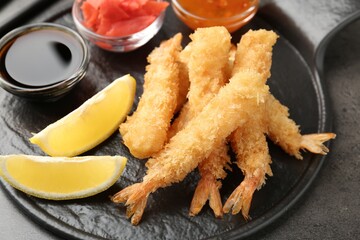 Tasty tempura shrimps, lemon, ginger and sauces on grey textured table, above view