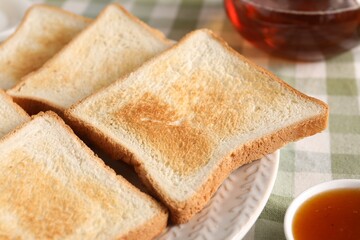 Slices of tasty toasted bread and jam on checkered tablecloth, closeup