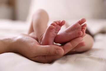 Mother with her little baby on bed indoors, closeup