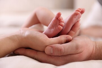 Parents with their little baby on bed indoors, closeup