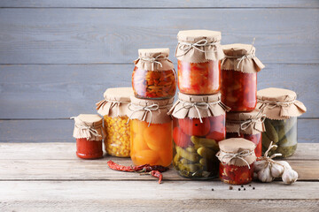 Many jars with different pickled products on wooden table