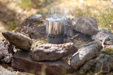 Fototapeta premium Steam coming out of camping stove making coffee standing in a camp fire site National Forest, stockholm, sweden