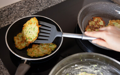 Image of process frying zucchini pancakes in frying pan in kitchen
