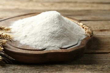 Wheat flour and spikelets on wooden table, closeup