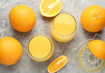 Orange juice in glasses, fresh fruits and juicer on grey table, flat lay