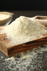 Pile of flour on dark table against black background, closeup