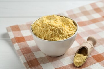 Corn flour in bowl and scoop on white table, closeup