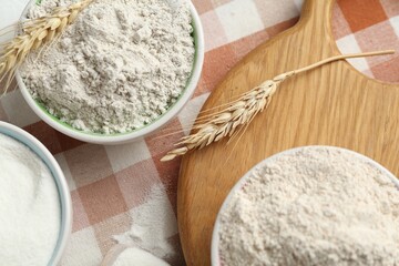 Different types of flour in bowls and spikes on table, flat lay