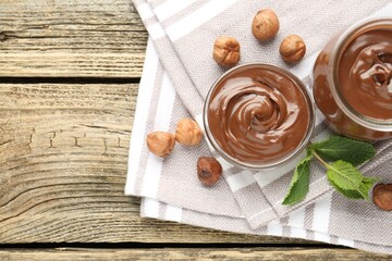 Tasty chocolate spread, hazelnuts and mint on wooden table, top view. Space for text