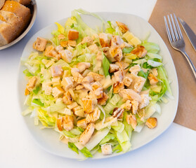 Appetizing caesar salad served on platter with parmesan cheese and chicken pieces