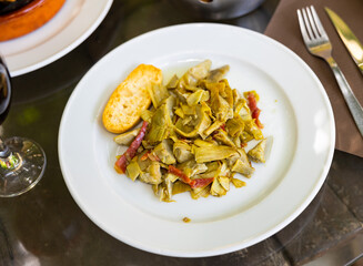 Appetizing fried artichoke served on platter with ham and bread
