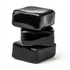 Dark gelatinous cubes of shilajit lie one on top of the other, high contrast with the white background.