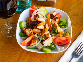Delicious healthy salad with grilled chicken fillet, cucumber, green padron pepper, tomatoes and onion..