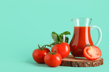 Jug of fresh tomato juice with basil and vegetables on turquoise background