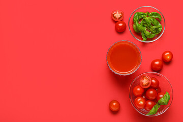 Glass of fresh tomato juice with basil and vegetables on red background