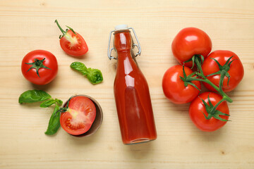 Bottle of fresh tomato juice with basil and vegetables on wooden background