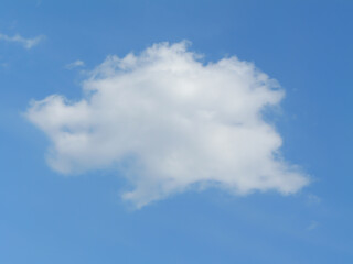 Fototapeta premium Soft white clouds drifting in a bright blue sky on a sunny day, ideal as natural backgrounds or design templates