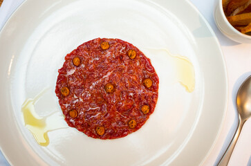 Dish from chefs neck of restaurant is veal tartare. Food is made from chopped raw veal fillet, capers, decorated with balsamic caramel. Gastronomy, haute French cuisine