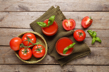 Glasses of fresh tomato juice with basil and vegetables on wooden background