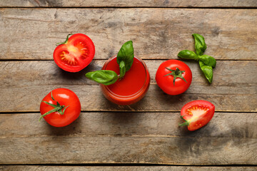 Glass of fresh tomato juice with basil and vegetables on wooden background