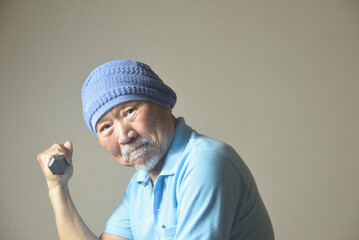 ダンベルを手に筋トレをする髭の老人