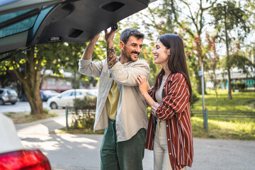 beautiful happy couple stand by the trunk and get ready to leave city