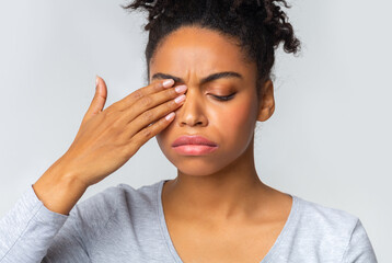 African girl rubs her eye, suffering from conjunctivitis, ocular diseases concept
