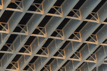 Underside of a modern cable-stayed bridge with sunlight reflecting on the infrastructure