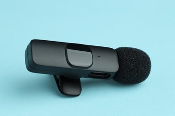 Lavalier microphone on light blue background, closeup