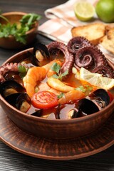Tasty seafood soup in bowl on wooden table, closeup