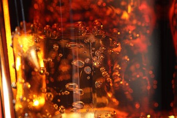 Refreshing cola with ice cubes as background, macro view