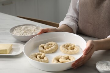 Woman with uncooked pretzels at table in kitchen, closeup