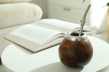 Traditional yerba mate tea and book on white table indoors