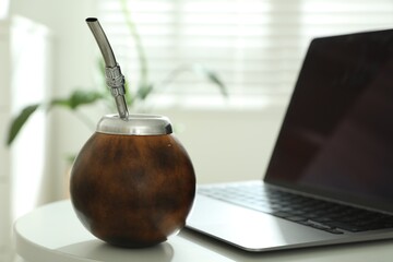Traditional yerba mate tea and laptop on white table, closeup