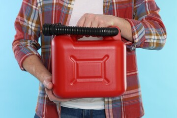 Man holding plastic canister on light blue background, closeup