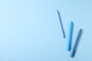 Stylish pens on light blue background, flat lay. Space for text