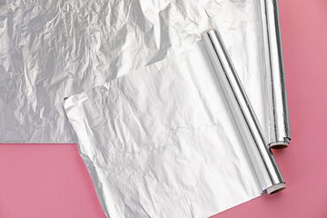 Rolls of aluminum foil on pink background, above view