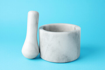 Marble mortar and pestle on light blue background, closeup