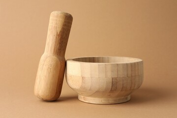 Wooden mortar and pestle on light brown background, closeup