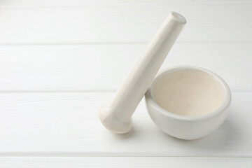 Ceramic mortar and pestle on white wooden table. Space for text